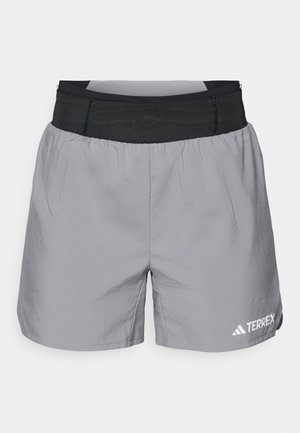 Grijze sportshorts met een elastische zwarte tailleband, lichtgewicht materiaal, een relaxte pasvorm en een witte logo-accent aan de onderzijde rechts.
