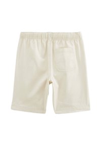Shorts en coton couleur crème avec une taille élastique, présentant une poche arrière unique et une texture lisse, coupés juste au-dessus du genou.