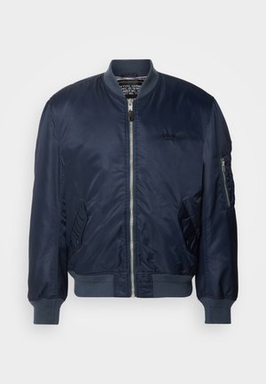 Marineblaue Bomberjacke aus glattem Nylon, mit einem Reißverschluss vorne, Seitentaschen, gerippten Bündchen und einer Ärmeltasche mit Reißverschluss.