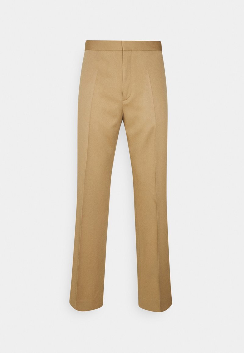 Pantalon beige sur mesure avec plis sur le devant, jambes droites et taille ajustée, présenté sur un fond clair uni.