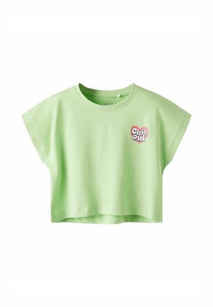 Camiseta corta de color verde claro, hecha de algodón. Presenta mangas cortas, cuello redondo y un gráfico de "Chill Out" en forma de corazón en la parte delantera.