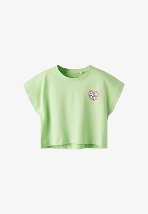 Camiseta corta de color verde claro, hecha de algodón. Presenta mangas cortas, cuello redondo y un gráfico de "Chill Out" en forma de corazón en la parte delantera.