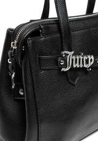 Czarna skórzana torebka o teksturowanym wykończeniu, srebrny zamek błyskawiczny i dekoracyjne logo 'Juicy'. Posiada sztywny kształt i podwójne uchwyty.
