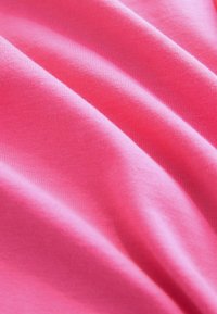 Lys rosa stof med en glat tekstur og let glans, der viser bølgede folder og et blødt, let design.