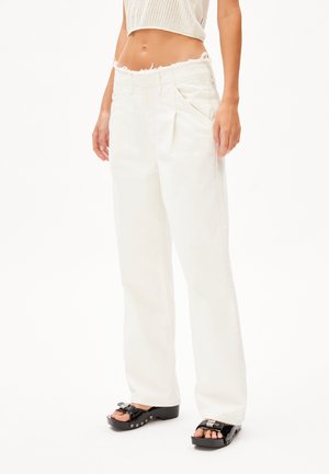 Witte hoge taille jeans met een rafelige tailleband, wide-leg pasvorm, zijzakken en een gladde textuur, gecombineerd met zwarte platform sandalen.