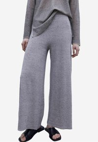 Pantaloni a gamba larga grigio chiaro realizzati in un morbido tessuto strutturato, caratterizzati da un design morbido e una vita alta.