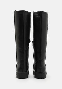 Bottes en cuir noir hauteur genou avec une finition lisse, dotées de fermetures éclair sur le côté et de semelles texturées, avec des coutures contrastées le long des bords.