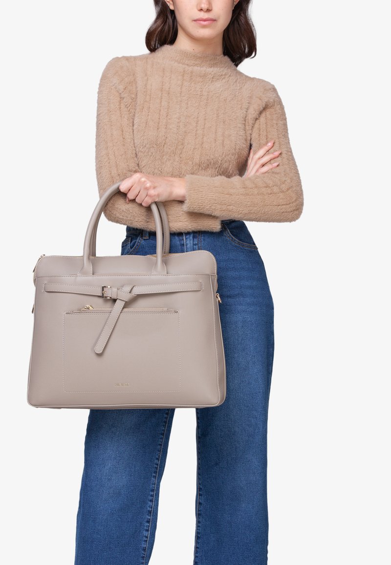 Beige læderhåndtaske med struktureret design, dobbelt håndtag, lynlås i toppen og frontlomme; tekstureret overflade og subtile gulddetaljer.