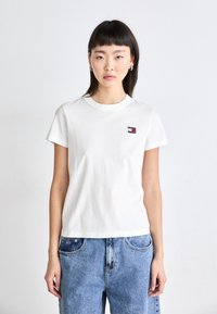 Witte katoenen t-shirt met korte mouwen, ronde hals en een klein rood en blauw logo op de linkerkant van de borst. Geschikt bij blauwe denim jeans.