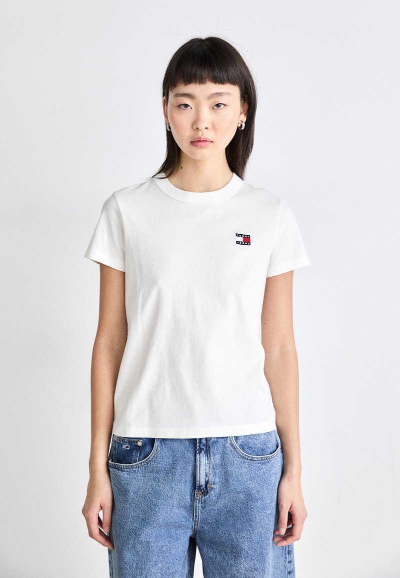 Witte katoenen t-shirt met korte mouwen, ronde hals en een klein rood en blauw logo op de linkerkant van de borst. Geschikt bij blauwe denim jeans.
