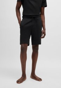 Mustat puuvillashortsit, joissa on joustava vyötärö ja kiristysnauha, sivutaskut sekä hieman rento leikkaus. Sujuva pinta ja polven pituus.