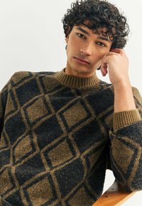Maglione lavorato a maglia con un motivo a diamante in blu scuro e marrone. Collo e polsini a costine, tessuto testurizzato con una finitura morbida.