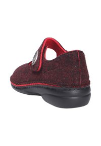 Pantofole in feltro di lana rosso e nero con forma curvata, aperture tonde e un bottone decorativo. Suola in gomma nera per una migliore aderenza.
