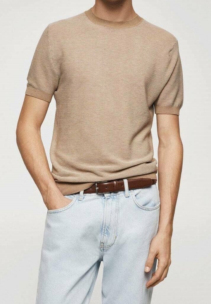 suéter de punto beige de manga corta con escote redondo, combinado con jeans de color azul claro y un cinturón de cuero marrón.