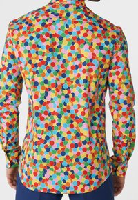 Camisa de botón colorida con un patrón vibrante de círculos de diferentes tamaños en rojo, azul, verde, amarillo y rosa sobre un fondo claro.