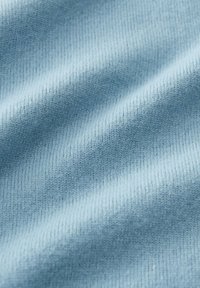 Nahaufnahme eines weichen, hellblauen Strickstoffs mit sichtbarer Textur und feinem Rippmuster.