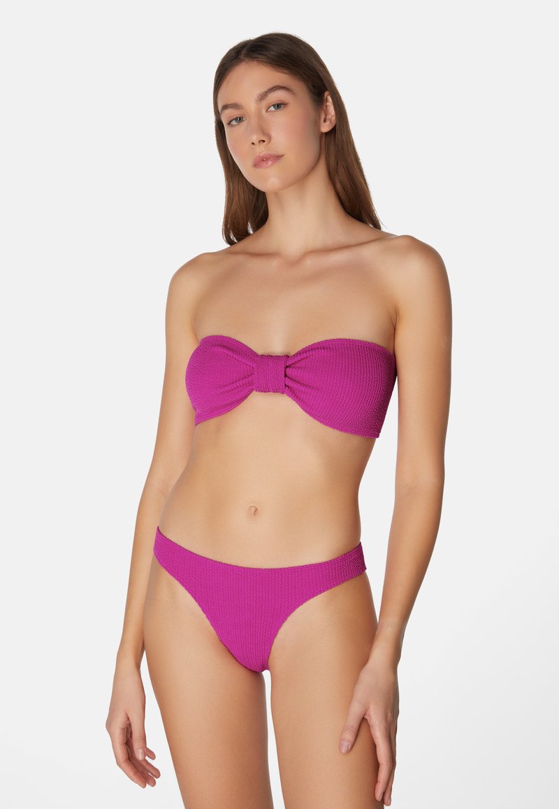 Rosa, stickad bandeau-bikini med en rosett detalj på toppen och matchande låghöga bottnar. Texturerad tyg med minimala accent.
