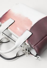 Fargeblokkerende veske med en rosa gradient, hvitt syntetisk materiale, sølv glidelåser og doble håndtak med kontrasterende detaljer.