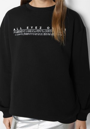 Black sweatshirt with long sleeves, ribbed neckline, and front graphic text design featuring "ALL EYEZ ON ME" in white. Soft texture.