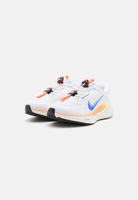 Hvite og oransje Nike joggesko med blå swoosh-logoer, svarte såler, og unik toggle-snøring på hvit bakgrunn.