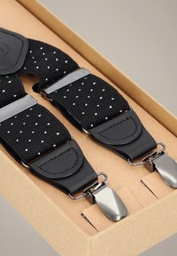 Czarne dziergane szelki ze srebrnymi klipsami, z wzorem diamentowym. Paski mają skórzane akcenty, zapakowane w kartonowe pudełko.