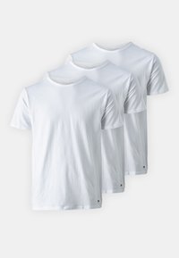 Trois t-shirts blancs en coton à manches courtes, avec des encolures rondes et un petit logo sur le bas à gauche. Textured lisse, coupe standard.
