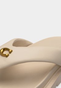 Μπεζ σαγιονάρα από TPU με χρυσό κόσμημα σε σχήμα πεταλούδας στο λουράκι και μαλακό ανατομικό πέλμα.