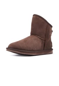 Botas de tobillo de ante marrón con puntera redondeada, textura suave y un caña corta. Presenta una costura y un detalle externo mínimo.