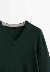 Pull vert foncé à col en V avec encolure côtelée et doublure intérieure de col gris clair, présenté sur un fond blanc.