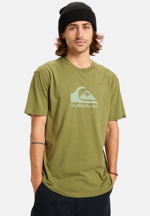 Camiseta verde oliva de algodón con cuello redondo, que presenta un gráfico del logo de Quiksilver en azul claro en la parte delantera. Corte casual y mangas cortas.