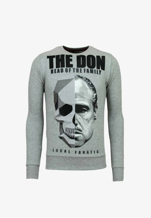 Grijze sweatshirt met een afbeelding van een schedel en een gezicht, met zwarte tekst die leest "DE DON HOOFD VAN DE FAMILIE" en "LOKALE FANATICUS."