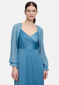 Robe longue et fluide en satin bleu, présentant un décolleté en V, un corsage plissé, et des manches bouffantes transparentes avec des détails aux poignets.