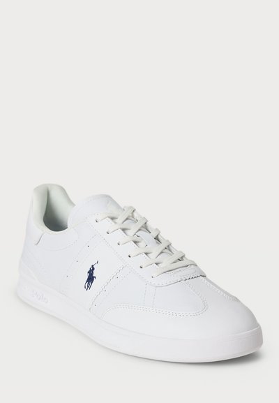 Balti odiniai sportbačiai su lygiu paviršiumi; turi tamsiai mėlyną logotipą, raištelių užsegimą ir suapvalintą nosį, įmontuoti ant guminio pado.