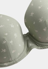Light green padded bra with small white floral patterns and underwire stitching on a plain background.