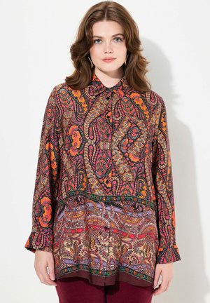 Blusa a maniche lunghe con un vivace motivo paisley in rosso, arancione e viola su uno sfondo scuro. Design con bottoni e orlo curvo.
