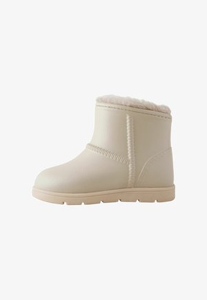 Beige enkellaars gemaakt van soepel leer met een zacht, met bont gevoerd bovenwerk. Kenmerkt sich door gestikte accenten en een gestructureerde rubberen zool.