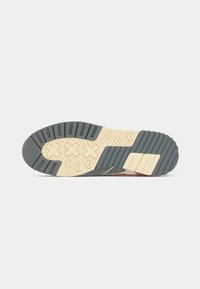 Grå sneaker sål med ribbet tekstur, der har en beige gummi overflade og geometrisk mønster for godt greb. Indeholder brandingdetalje på siden.
