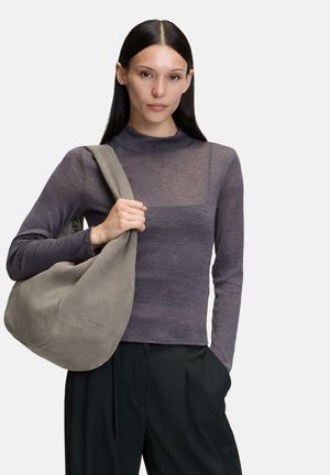 Borsa a spalla in suede grigio con una forma morbida e arrotondata. Il modello indossa un top fitted a maniche lunghe grigio scuro con un collo alto e una sottile texture.