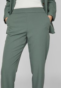 Ljust gröna skräddarsydda byxor i ett slätt tyg. Har framfickor och en plan framsida med slim fit.