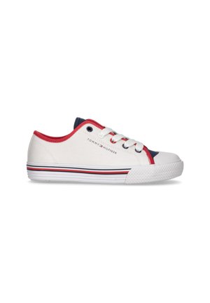 Zapatilla de lona blanca con acentos rojos y marinos, punta redonda, tres ojetes blancos y una suela de goma texturizada con rayas.
