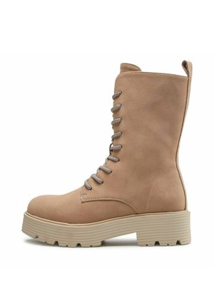 Beiger Wildleder-Stiefelette mit Schnürung, dicker Gummisohle und Zugschnalle hinten, Seitenansicht vor weißem Hintergrund.