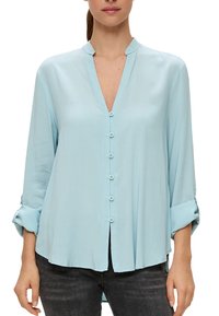 Helles blaues Bluse mit V-Ausschnitt, langen Ärmeln, die an den Manschetten hochgerollt sind, und einer durchgehenden Knopfleiste. Glatte Textur und lockere Passform.