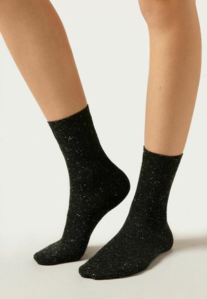 Schwarze Socken mit einem strukturierten, gesprenkelten Muster in Silber. Knöchelhöhe und mit gerippten Bündchen. Weiches Material für Komfort.