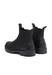 Botas Chelsea negras con cuero liso, paneles laterales elásticos y lengüetas. Suelas de goma gruesa con un diseño de suela para mejorar la tracción.