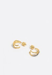 Pendientes aros de oro y plata con un diseño texturizado y ondulado y cierres cilíndricos. Presentan una combinación de acabados pulidos y mate.