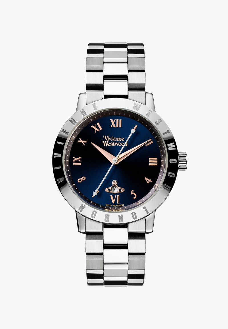 Ανοξείδωτη ρολόι χειρός με ναυτικό μπλε καντράν, ασημί δείκτες ωρών και βουρτσισμένο μεταλλικό μπρασελέ. Διαθέτει ένδειξη ημερομηνίας στις έξι.