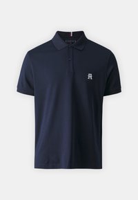 Polo tričko v námořnické modři vyrobené z bavlny, s tříknoflíkovým zapínáním, krátkými rukávy a malým vyšitým logem na levé hrudi.