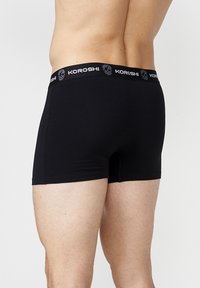 Fekete pamut boxer nadrág puha rugalmas derékkal, koponya mintával; sima textúra és testhez álló fazon.