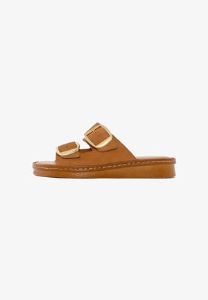 Bruine suède slidesandalen met twee verstelbare banden, gouden gespen, een gestructureerde zool en een dikke platte basis voor ondersteuning.