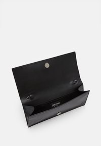 Svart läderplånbok med en slät textur, öppen för att avslöja en central ficka och silverfärgad tryckknappsstängning. Har en varumärkesetikett inuti.